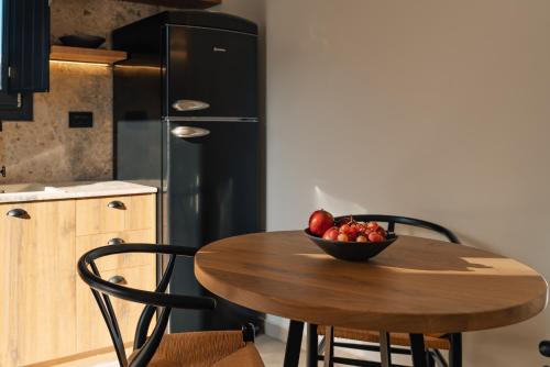 a kitchen with a wooden table with a bowl of fruit at Erthā Suites with private pools in Vóthon
