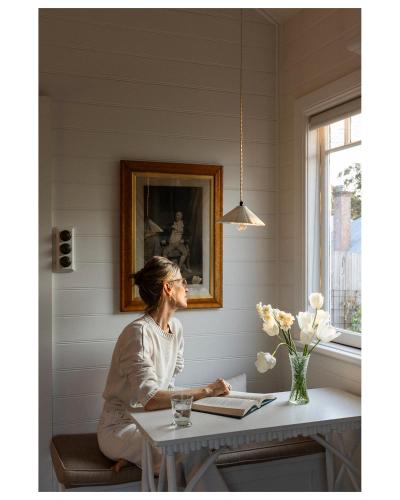 a woman sitting at a table in a room at The Potting Shed at Bunya House in Bowral