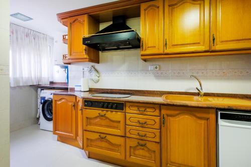 a kitchen with wooden cabinets and a stove top oven at Winahost Valencia El Puig 1 in El Puig