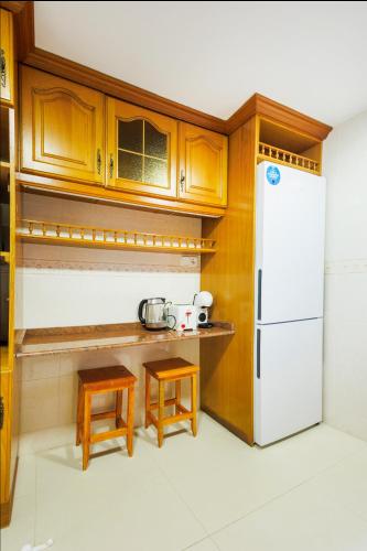a kitchen with a white refrigerator and wooden cabinets at Winahost Valencia El Puig 1 in El Puig
