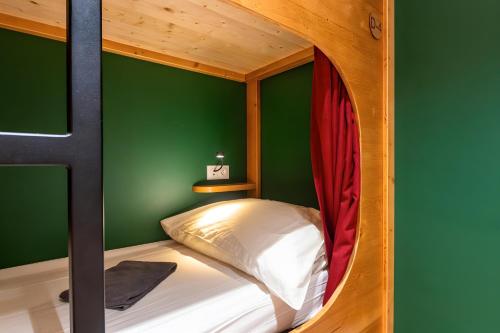 a room with a bunk bed with a green wall at Privatisation Hostel in Faverges