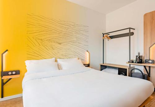 a bedroom with a white bed and a yellow wall at B&B HOTEL Le Touquet in Cucq