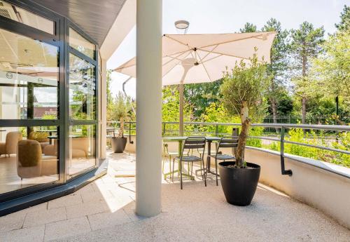 a patio with a table with a potted plant and an umbrella at B&B HOTEL Le Touquet in Cucq