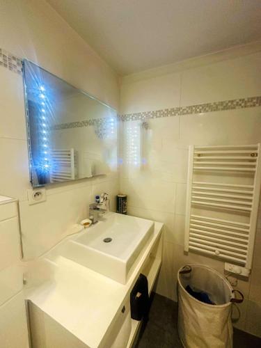 une salle de bain blanche avec un lavabo et un miroir dans l'établissement Bel appartement proche de la mer, à Monticello