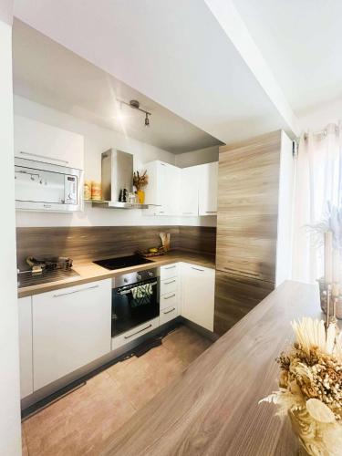 une cuisine avec des armoires blanches et une table en bois dans l'établissement Bel appartement proche de la mer, à Monticello