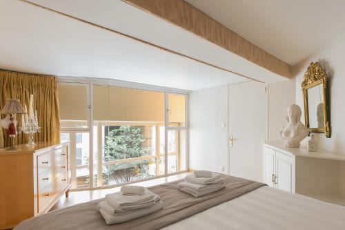 une chambre avec un lit et une grande fenêtre dans l'établissement Louvre Apartments, à Paris