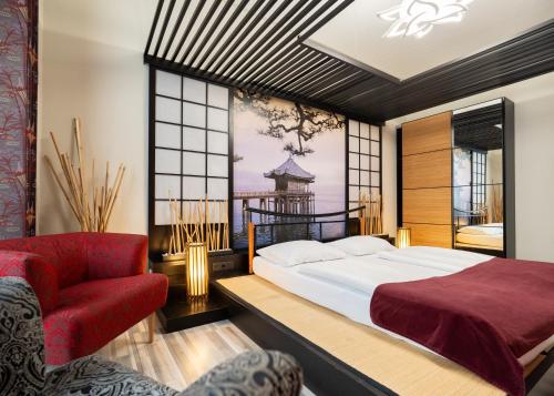 a bedroom with a large bed and a red chair at Hotel Urania in Vienna