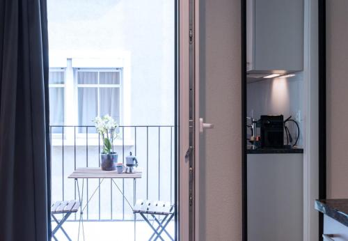 a door leading to a balcony with a table and flowers at HITrental Central Station Apartment in Zürich