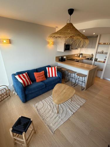 a living room with a blue couch and a kitchen at Appartement face mer in Saint-Jean-de-Monts