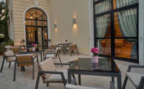 a patio with tables and chairs and tables and windows at Volos Palace in Volos