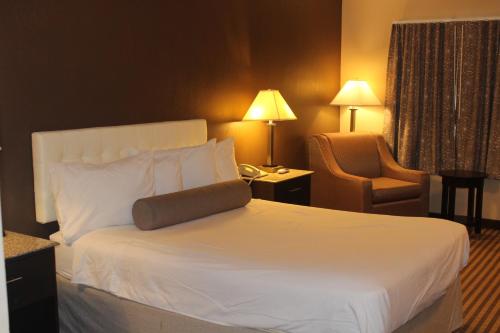 a hotel room with a white bed and a chair at Travelodge by Wyndham Bellmawr in Bellmawr