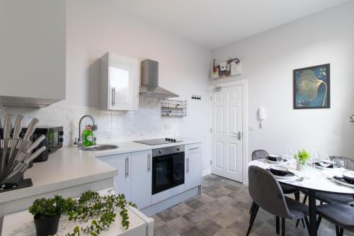 a white kitchen with a table and a dining room at Open Mind Property - Apartment with 2 Double Beds in Portsmouth