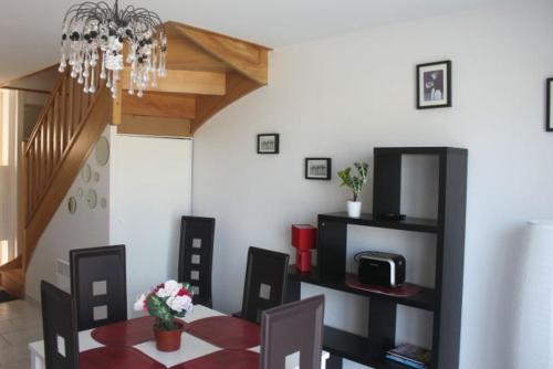 une salle à manger avec une table, des chaises et un lustre dans l'établissement maison de la mer, à Quend-Plage