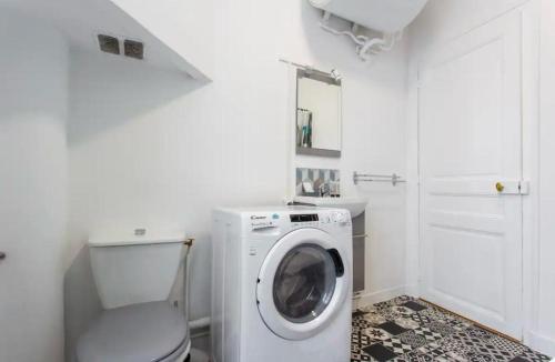 - une buanderie blanche avec un lave-linge dans l'établissement Le Raspail - Charmant appartement proche Paris, à Levallois-Perret