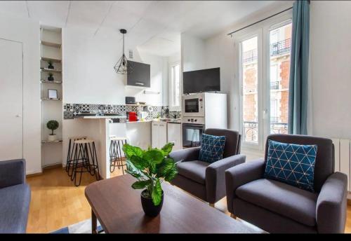un salon avec des canapés et une table ainsi qu'une cuisine dans l'établissement Le Raspail - Charmant appartement proche Paris, à Levallois-Perret