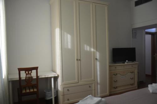 a bedroom with a large white cabinet and a television at Hotel Cordova in Florence