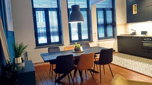 a dining table and chairs in a kitchen with windows at Royal South II - Stylish apartment in Antwerp Zuid in Antwerp