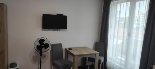a living room with a table and a tv on the wall at Apartmani METRO in Loznica