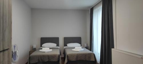 two twin beds in a room with a window at Apartmani METRO in Loznica