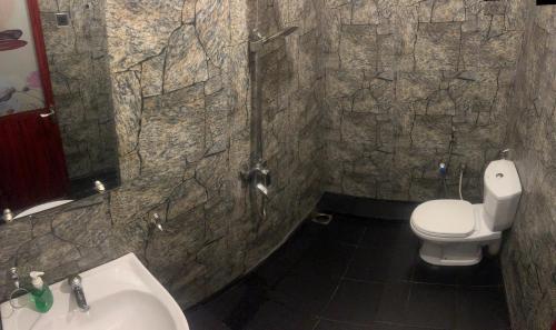 a stone bathroom with a toilet and a sink at MUM Jungle Inn in Ella