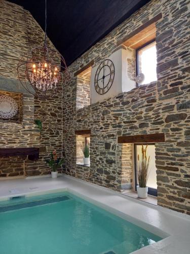 - une piscine dans une pièce dotée d'un mur en pierre et d'une horloge dans l'établissement Domaine de Meros, à Plonévez-du-Faou
