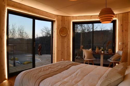 a bedroom with a large bed and a large window at Domaine des Étoiles - Logements Insolites in Gillonnay