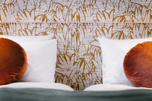 two pillows on a bed next to a wall at 1.75 Paris La Trêve in Paris
