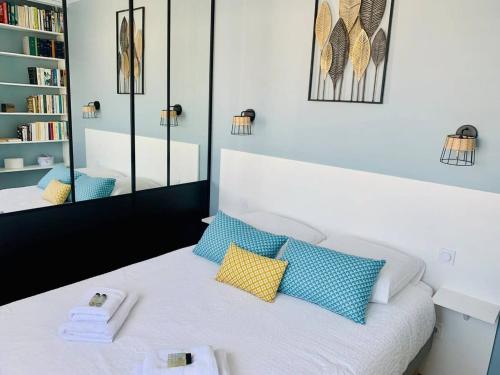 une chambre avec un lit avec des oreillers bleus et jaunes dans l'établissement Le Treich Laplene - Parking Wifi, à La Rochelle