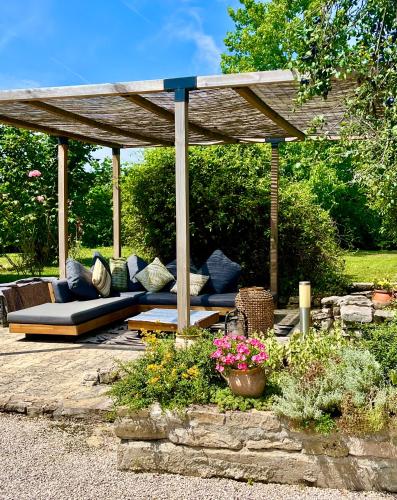a wooden pergola with a couch in a garden at La Longère de Bourgogne in Demigny