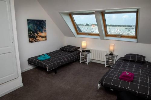 deux lits dans une chambre avec deux fenêtres dans l'établissement Le Grand Lazaret Vue Mer - Wifi, à La Rochelle