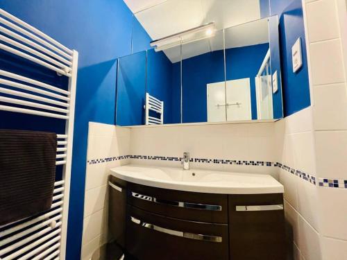 La salle de bains bleue et blanche est pourvue d'un lavabo et d'un miroir. dans l'établissement Le Grand Lazaret Vue Mer - Wifi, à La Rochelle