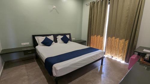a bedroom with a bed with blue pillows and a window at MAHA RAAS A unit of RAAS LEELA Hotels and Resort in Udaipur