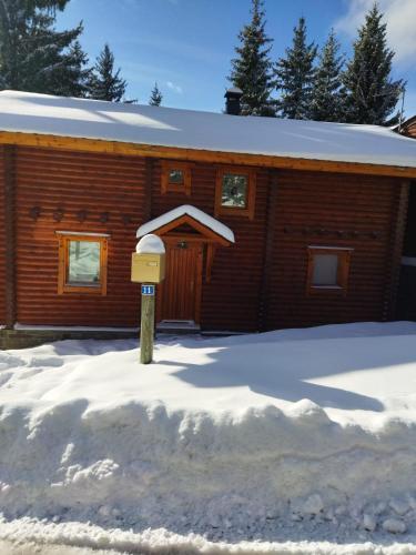 une cabane en rondins dans la neige avec une boîte aux lettres dans l'établissement Chalet de charme authentique, à Bolquère-Pyrénées 2000