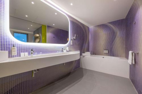 a purple bathroom with a tub and a sink and a mirror at Park Inn by Radisson Amsterdam City West in Amsterdam