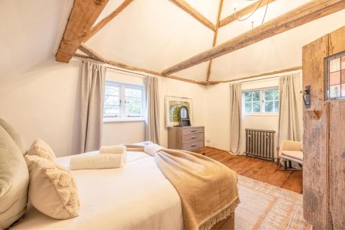 a bedroom with a bed and two windows at Cosy 5 Bed Cottage Retreat, Perfect for Families in Buckinghamshire