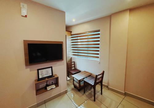 a living room with a table and a tv on the wall at IvyArk Residency in Pinangode
