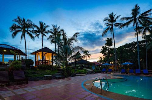 a pool with a slide in a resort with palm trees at Blue Star Dive and Resort in Anda