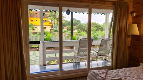 a room with a large window with chairs on a balcony at Aranya Abode in Arambol