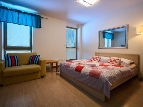 a bedroom with a bed and a couch and windows at Studio Harrachov by Interhome in Harrachov