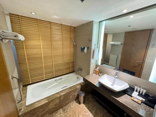 a bathroom with a tub and a sink and a bath tub at Radisson Blu Chattogram Bay View in Chittagong