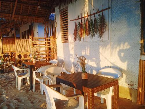 a restaurant with wooden tables and white chairs at Amwani Camping Site in San Vicente