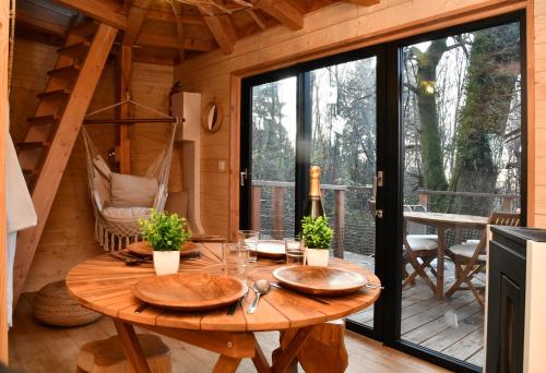 a dining room with a wooden table in a cabin at Domaine des Étoiles - Logements Insolites in Gillonnay