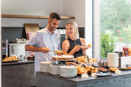 a man and woman standing in a kitchen preparing food at OLEEVA Garda Living - Adults Only in Riva del Garda