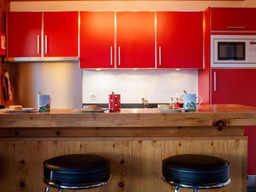 a kitchen with red cabinets and a counter with stools at Chalet Crettamour by Interhome in Veysonnaz