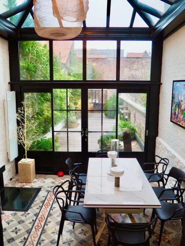 une table et des chaises dans une pièce avec une grande fenêtre dans l'établissement Villa Jouvence, à Le Touquet-Paris-Plage