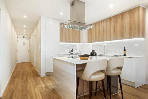a kitchen with white cabinets and a counter with stools at Sunset Vista 604 in Funchal