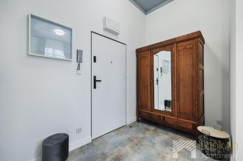 a room with a wooden cabinet and a mirror at Kolorova Apart by LookAp - darmowy parking w centrum Łodzi! in Łódź