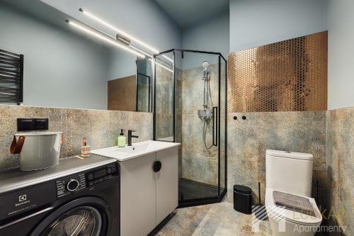 a bathroom with a washing machine and a shower at Kolorova Apart by LookAp - darmowy parking w centrum Łodzi! in Łódź