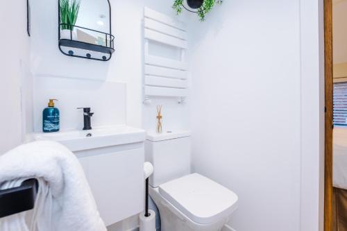 a white bathroom with a toilet and a sink at Foden's House by YourStays - 2 Bedroom Cottage in Sandbach with gorgeous dining room extension, High end finish in Sandbach