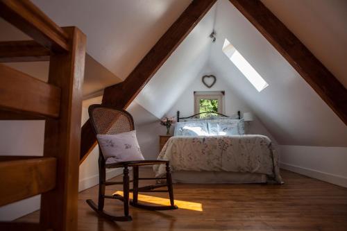 1 dormitorio en el ático con 1 cama y 1 silla en Moulin De Villesaint, en Faux-la-Montagne